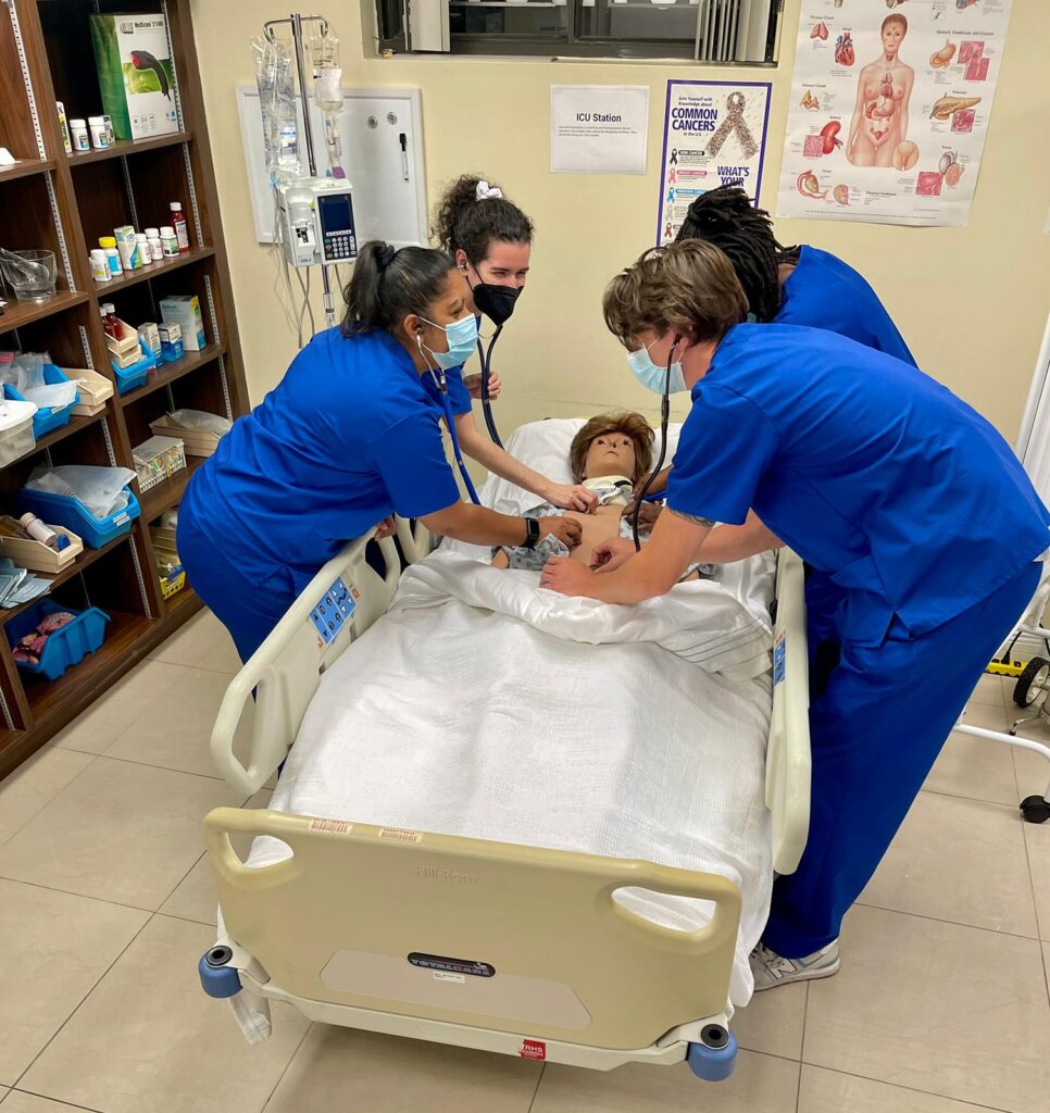 Nurses practicing clinical skills on a manikin in a skills lab