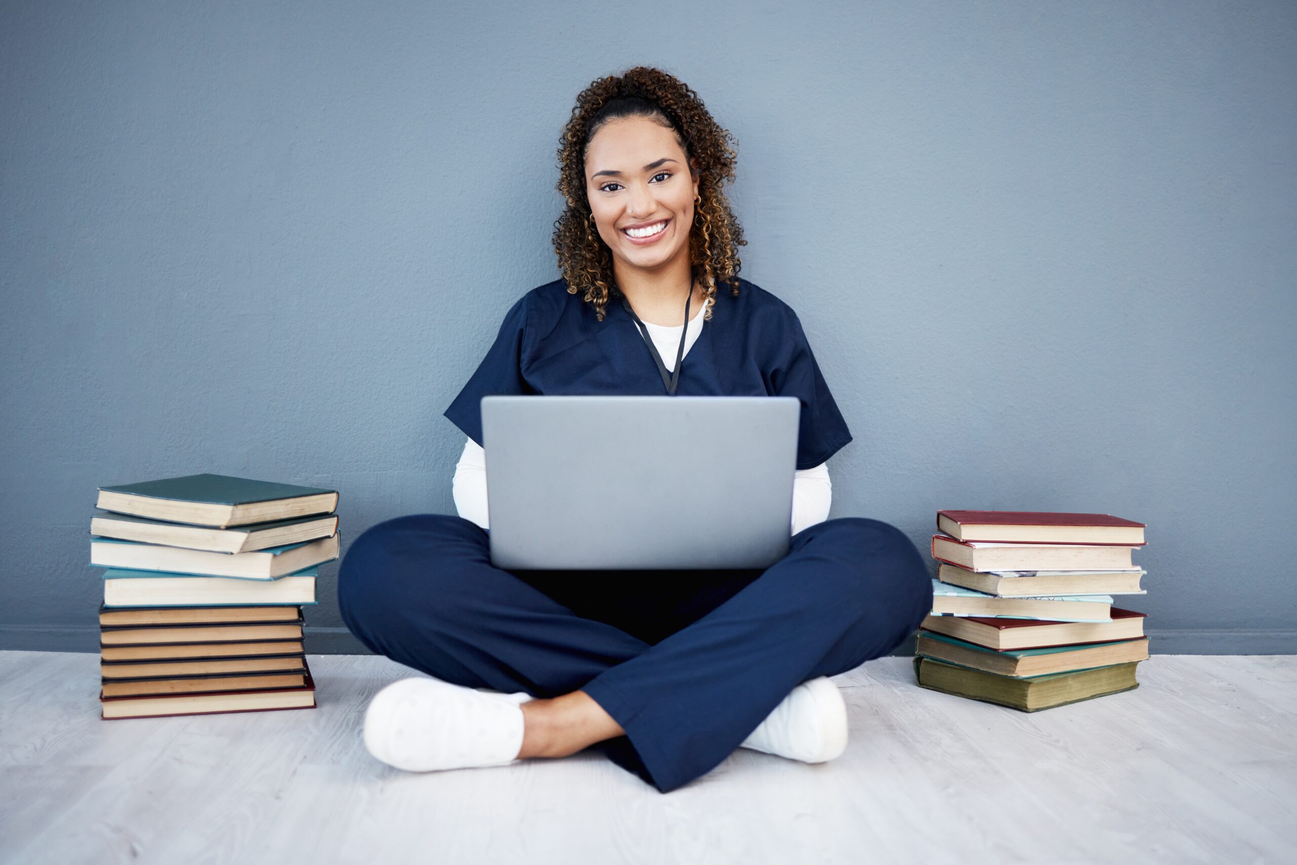 Nursing student with books and a laptop at Chancellor Institute